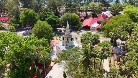 las imágenes de drones capturan el templo de wat nay harn en phuket, tailandia, rodeado de exuberante vegetación y vibrantes techos rojos bajo la brillante luz del día.
