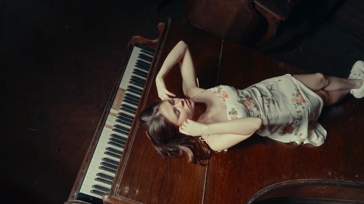 Dreamy Young Woman Posing on a Vintage Grand Piano