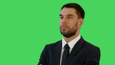 mid closeup shot of a profile of businessman in a tailored suit crossing arms on his chest and smiling warmly. shot on a green screen background.