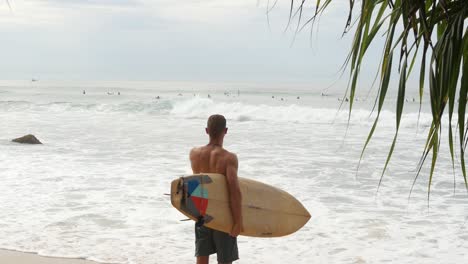 Male-Model-Holding-Surfboard-on-Sandy-Beach-in-Sri-Lanka