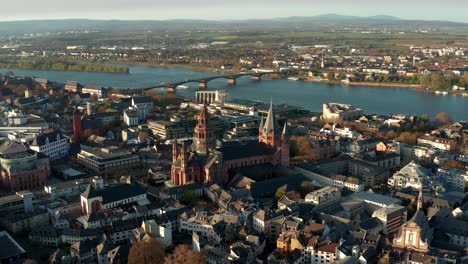 An-Einem-Warmen-Frühlingstag-Mit-Drohnenaufnahmen-Näher-An-Den-Mainzer-Dom-Heranfliegen,-Die-Den-Blauen-Fluss-Im-Hintergrund-Zeigen