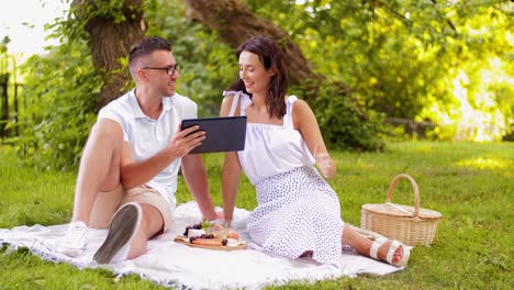 Glückliches-Paar-Mit-Tablet-PC-Beim-Picknick-Im-Park.Freizeit--Und-Personenkonzept-Glückliches-Paar-Mit-Tablet-PC-Beim-Picknick-Im-Sommerpark