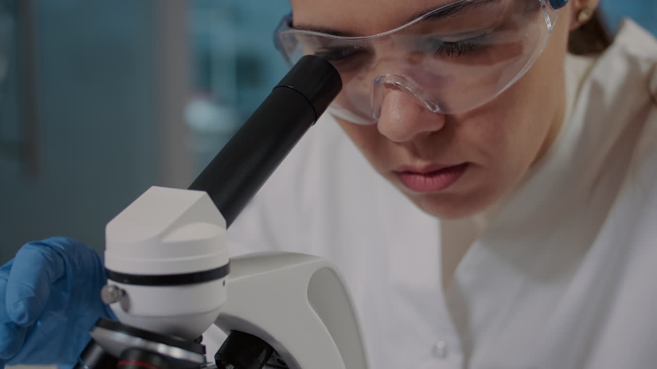 Woman looking through microscope lens to analyze dna sample