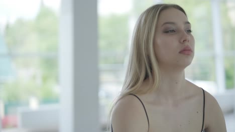 chica en forma con ropa negra actuando contemporáneamente. bailarina muestra movimientos fluidos, cuerpo y manos ondas en la habitación blanca. coreografía de danza de ballet moderno. joven se mueve suavemente