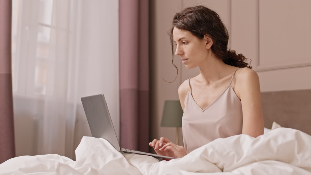 침대에 노트북으로 일하는 여자