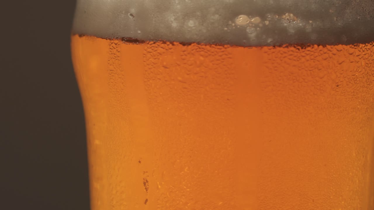 clsoe up shot de pinta de cerveza dorada con espuma girando sobre plataforma giratoria