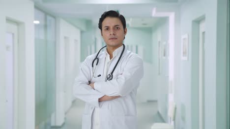 portrait of confident indian doctor standing crossed hands