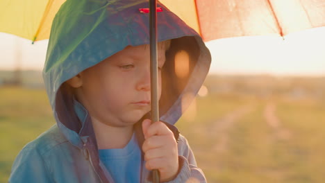 boy unease amplifies with rain tapping sound sad child stands alone under umbrella on riverbank with