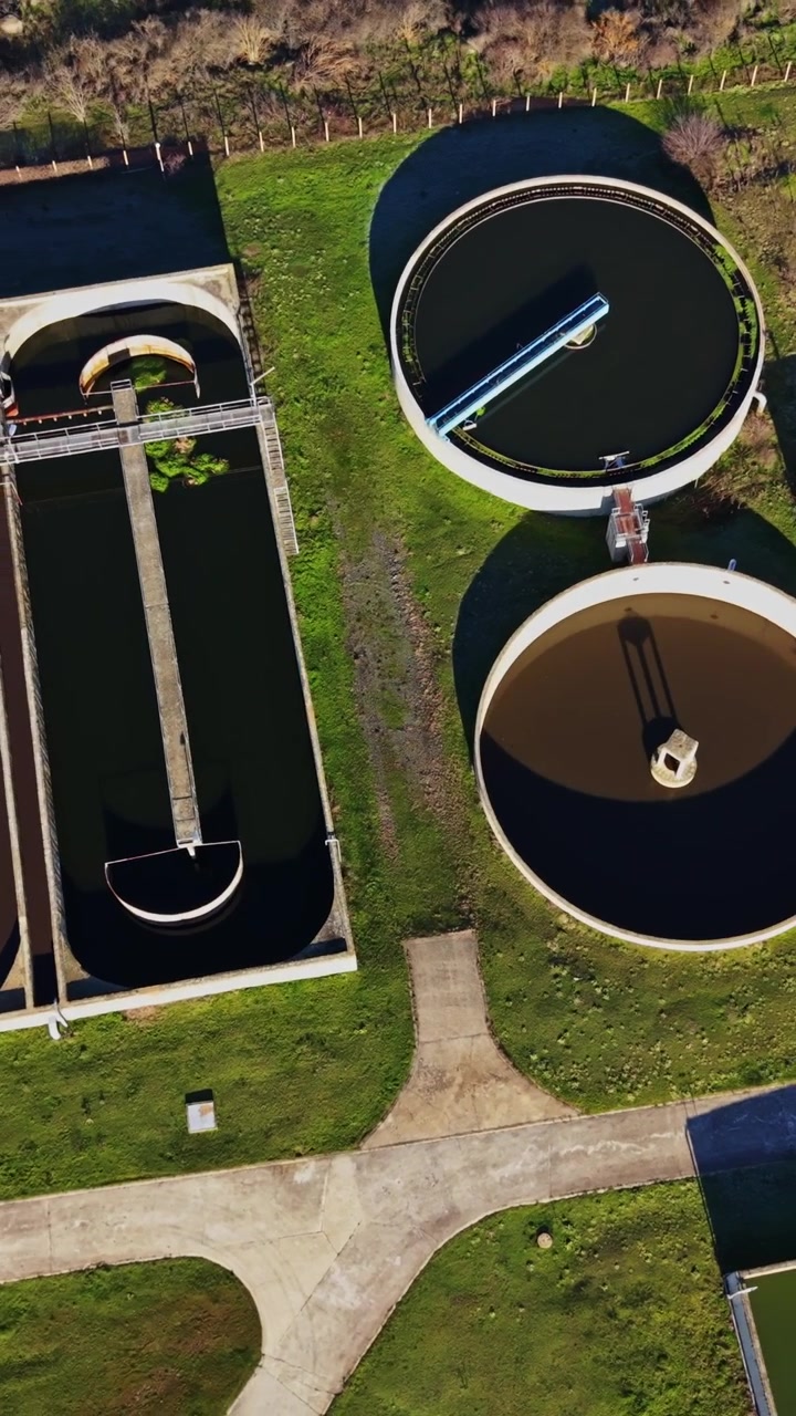 Water treatment facility with processing tanks and green fields nearby