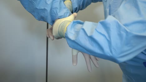 nurse assisting doctor and helping with tight gloves in medical room at hospital