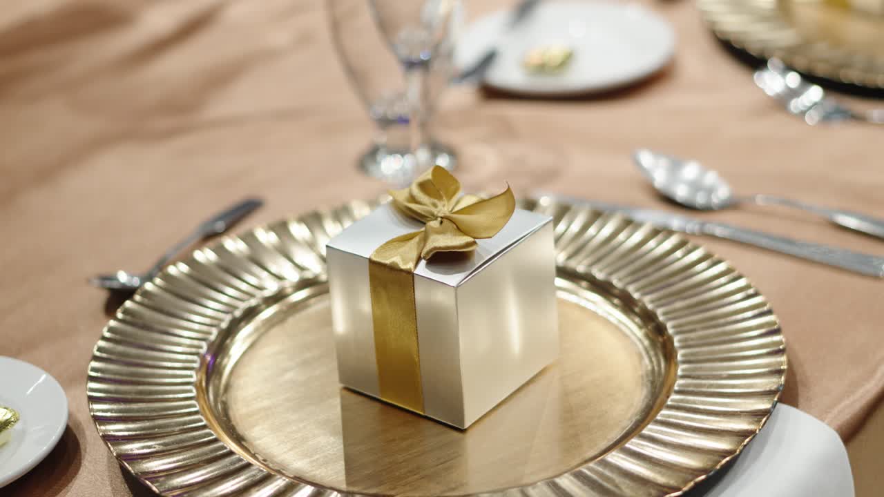 A small gift box for guests next to cutlery at a wedding dinner