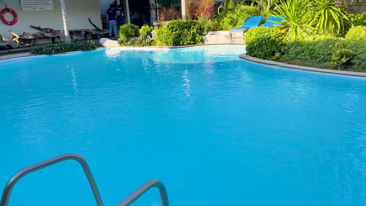 Bredt skud af en lysblå swimmingpool på et tropisk feriested i Thailand