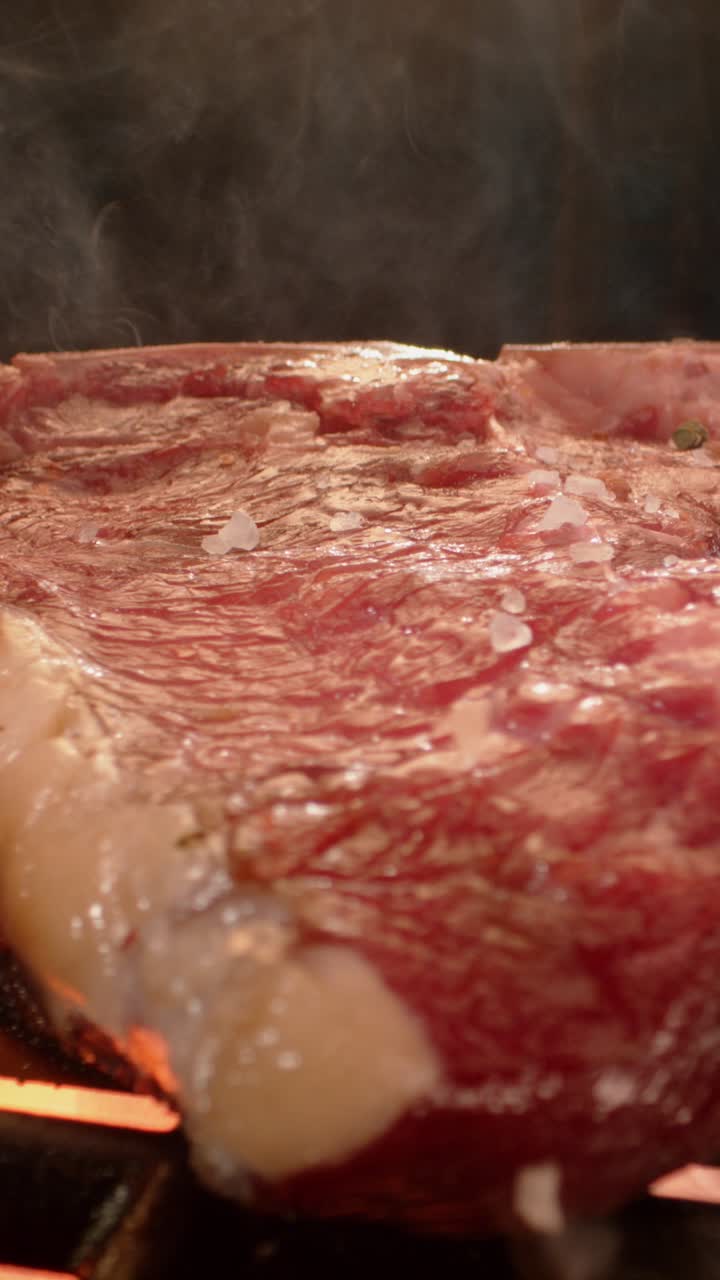 Steak being grilled with salt and seasoning