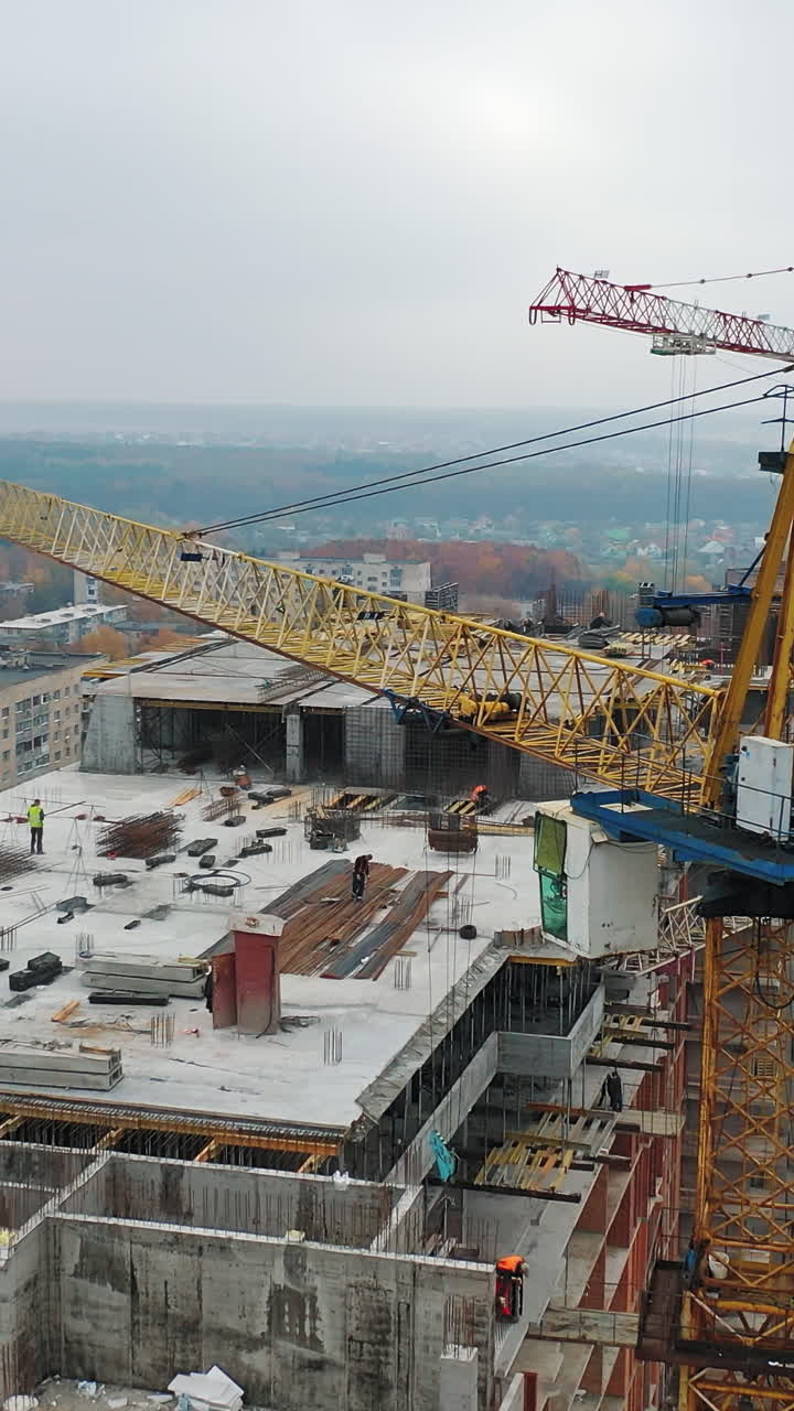 View from above on construction site with crane. Big construction crane on a building background. Aerial view. Slow motion. Vertical video