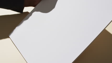 Video-of-hand-of-african-american-man-holding-book-with-blank-pages,-copy-space-on-yellow-background