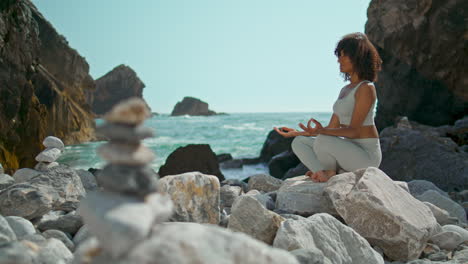 niña relajada sentada en la postura del loto en la playa vertical de la piedra ursa. mujer meditando