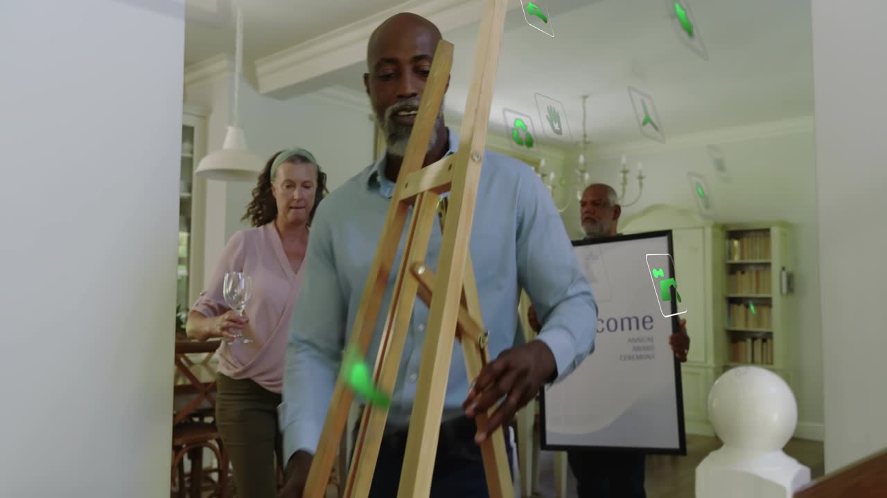 Senior gesturing man moving easel for event, woman carrying glasses, green overlays guiding setup