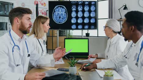 equipo multiétnico de científicos médicos usan pantalla de computadora de clave de croma verde durante la consulta conjunta en la oficina de la clínica