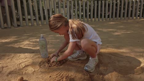 little girl playing in a playground, making constructions with sand and water