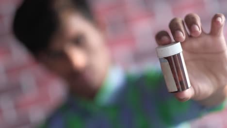 niño con una botella de pastillas