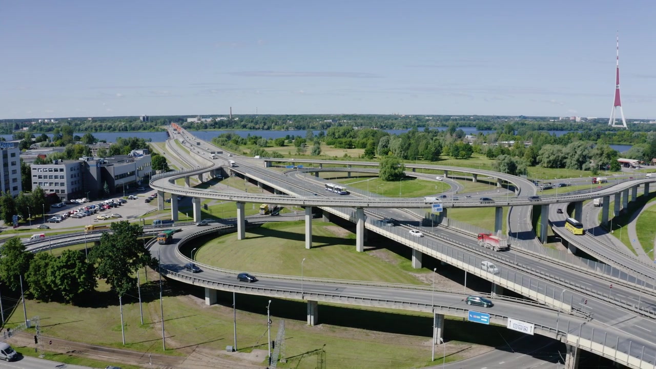 Aerial view of urban highway overpass crossing near Daugava River and landmark radio tower in Riga, Latvia.