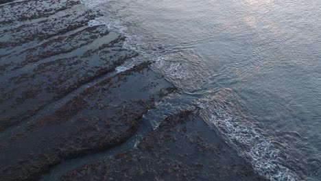 Panning-Drone-shot-of-Bingin-Beach-low-tide-reef-at-sunset-in-Uluwatu-Bali-Indonesia