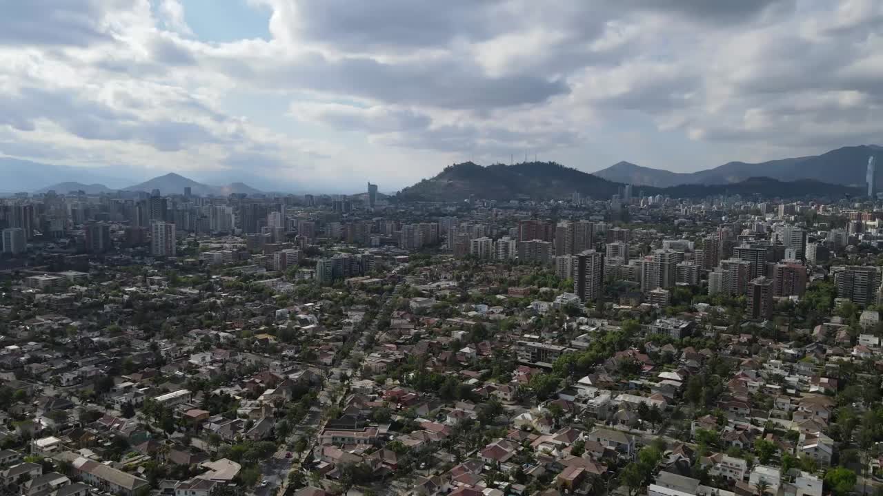 L'espansione urbana di Santiago, Cile, si estende sotto un cielo nuvoloso, mostrando edifici residenziali e commerciali.