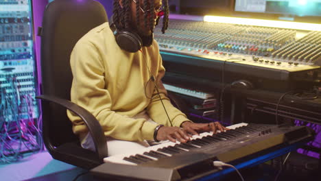 african american man playing synth in recording studio