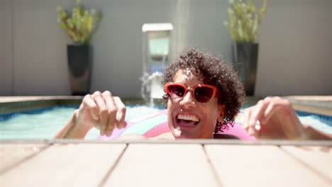 smiling man in sunglasses enjoying swimming pool on sunny day