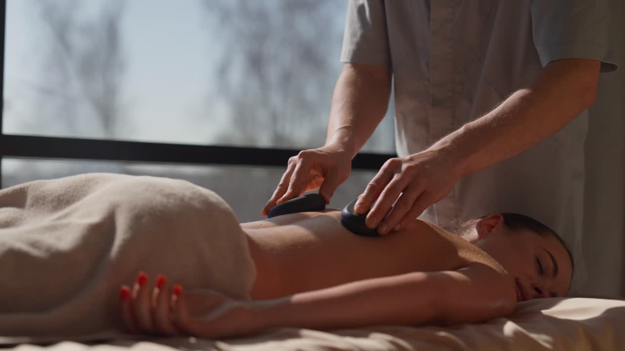 Donna che riceve un massaggio alla schiena con pietre calde in una spa
