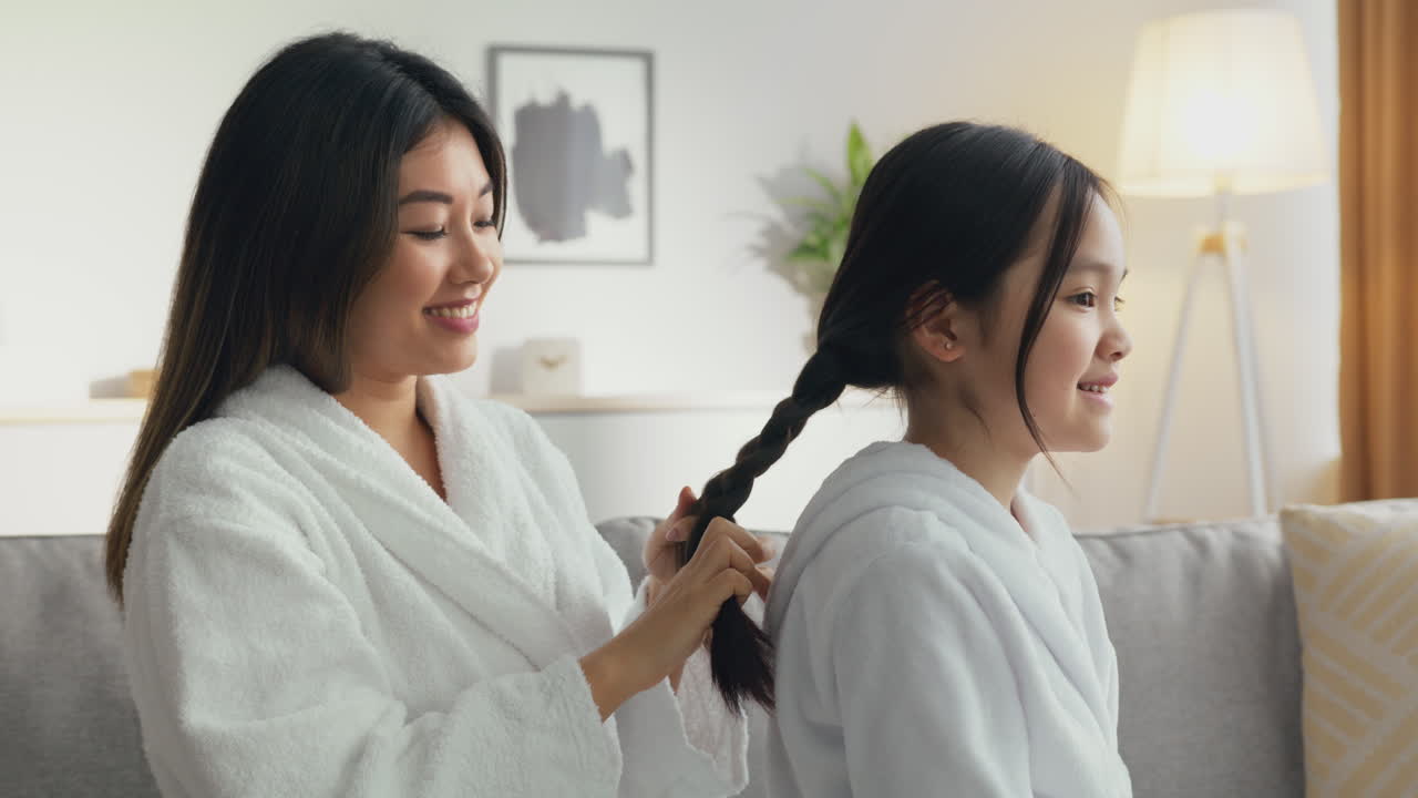 어머니가 딸의 머리카락을 고 있습니다.