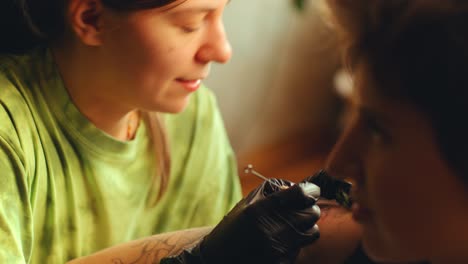 woman doing hand-poked tattoo for female client in studio