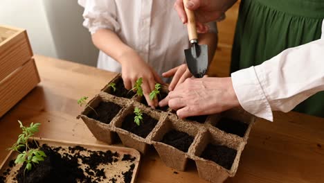 unrecognizable woman with child standing near wooden table with soil