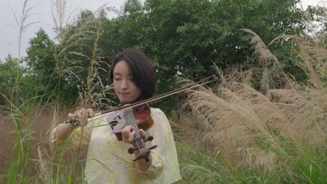 adolescente asiática tocando el violín