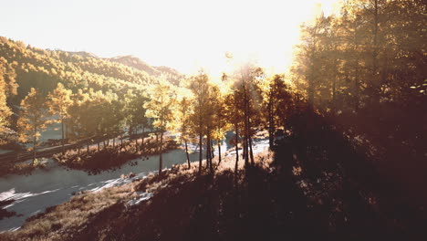 Tal-Mit-Herbstbäumen-Zwischen-Den-Bergen,-Die-Bei-Sonnenuntergang-Von-Der-Sonne-Beleuchtet-Werden