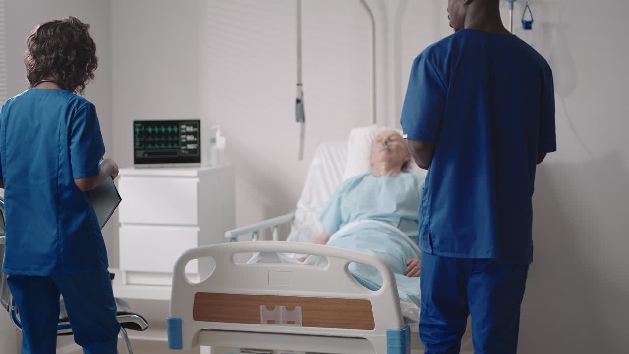 equipo médico étnico africano al lado de la cama de un paciente de edad avanzada. los proveedores de atención médica monitorean los signos vitales de un paciente de edad avanzada del hospital.