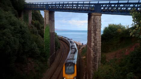 GWR-high-speed-train-from-Paddington-to-Penzance-passes-under-Eastcliff-Walk-bridge,-Teignmouth,-Devon,-UK