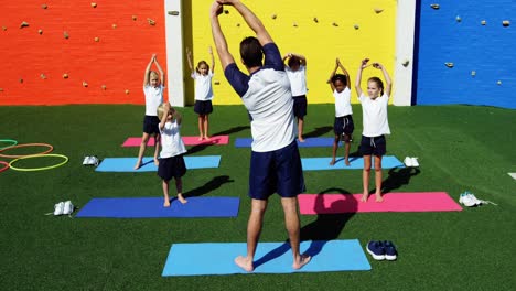 instructor de yoga instruyendo a los niños en la realización de ejercicios