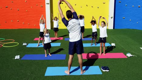 yoga instructor instructing children in performing exercise