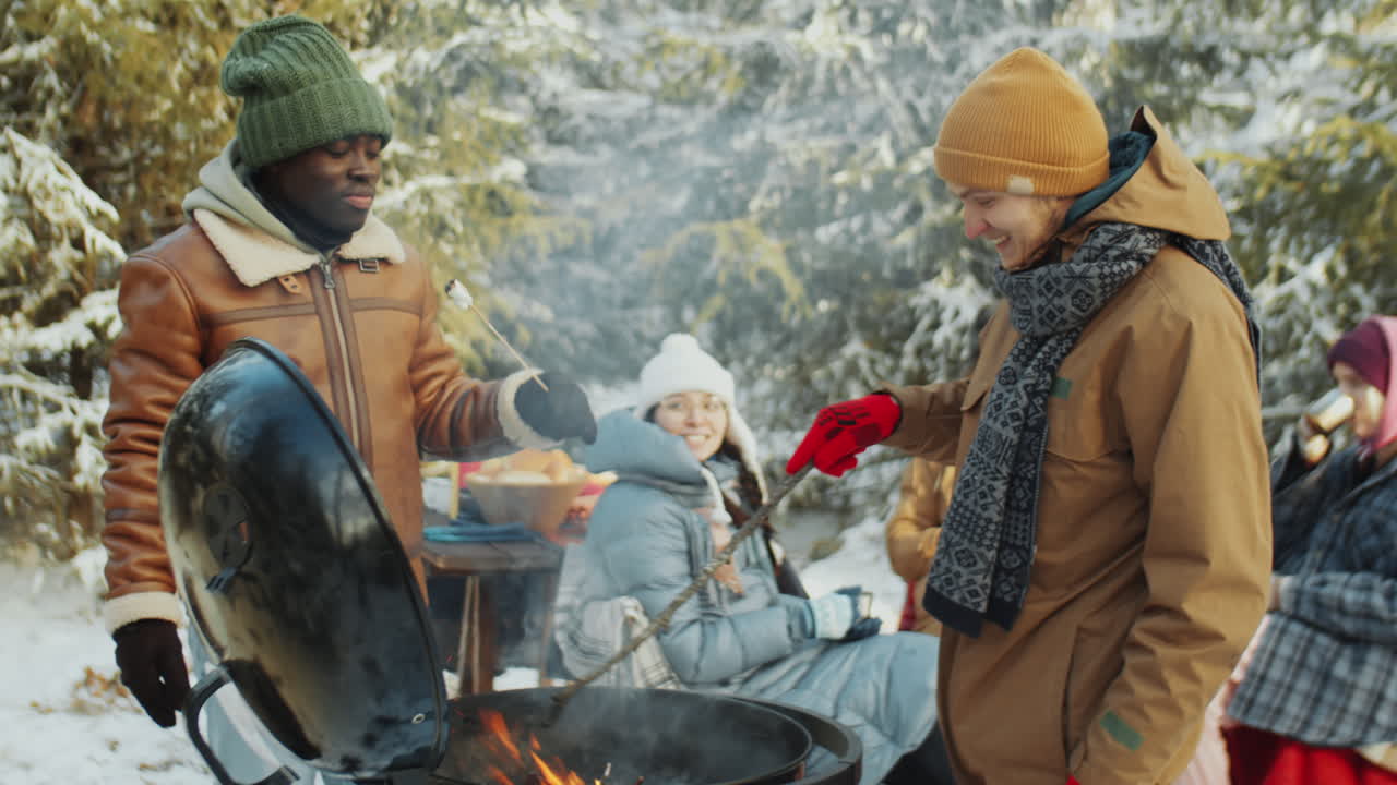 숲에서 겨울 피크닉에 bbq 그릴에 의해 먹고 대화하는 남자