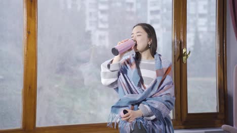 happy asian young woman watching snowfall by the window.