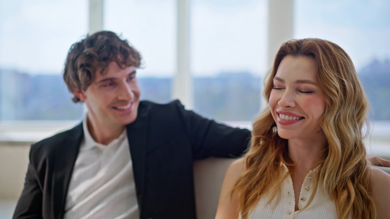 Coppia innamorata che chiacchiera sul divano dell'appartamento. Uomo e donna sorridenti che parlano insieme a casa