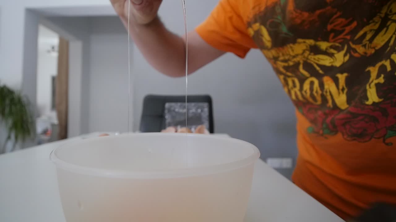 수컷 손이 흰색 계란을 그릇에 넣고 슬로우 모션으로 깨뜨립니다.