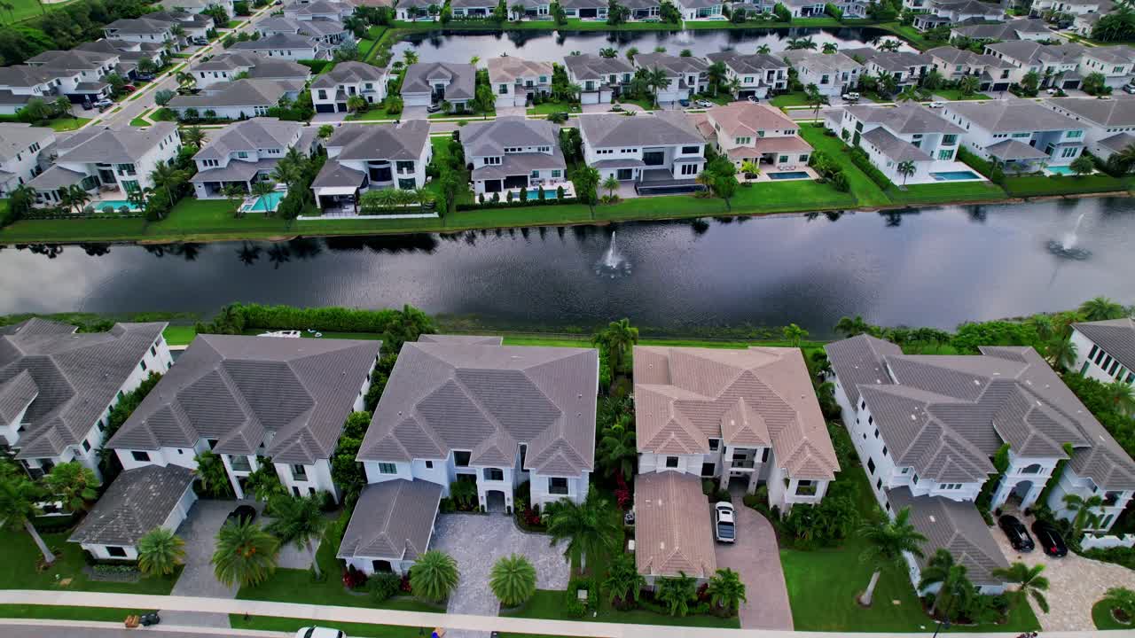 Aerial: residential area, lake and grey mansions during the day in Boca Raton, West Palm Beach, Florida, USA, establishing drone shot