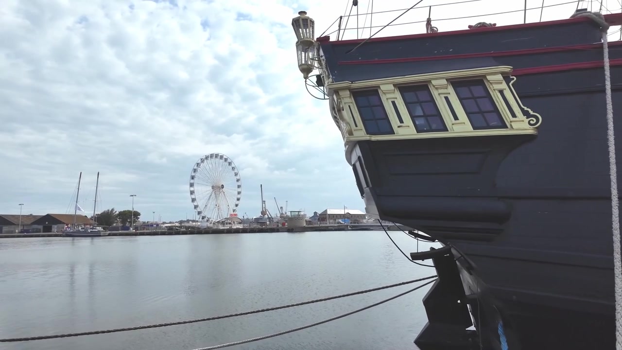 Poppa di una nave pirata in legno nera, ora attrazione turistica, e ruota panoramica in lontananza, Saint Malo, Francia