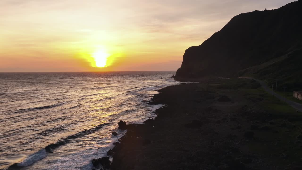Drone wide shot showing golden sunset at horizon along rocky coastline in Taiwan