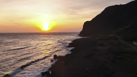 Drone-wide-shot-showing-golden-sunset-at-horizon-along-rocky-coastline-in-Taiwan