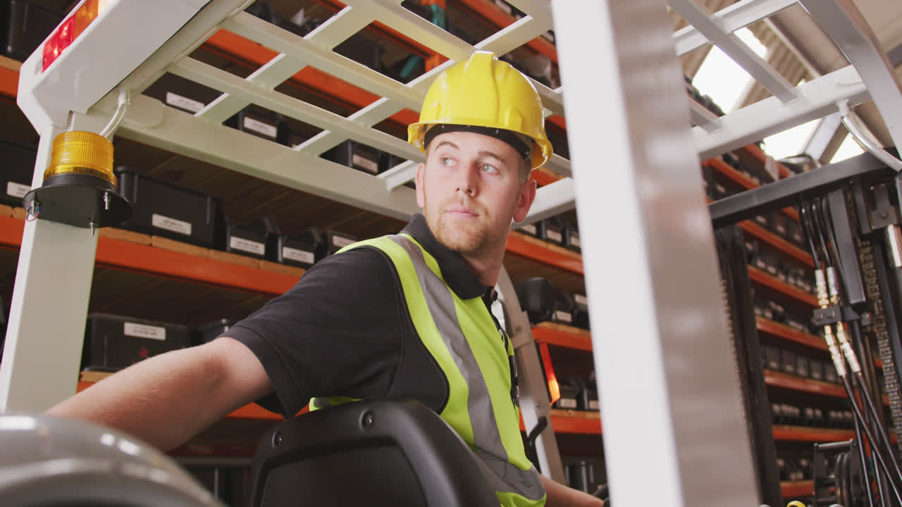Caucasian male factory worker at a factory with a hat and high vis vest, using a truck