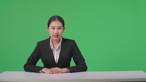 live news studio with professional asian female anchor reporting on the events of the day on the green screen