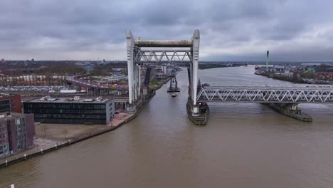 Aerial-view-of-tug-boat-and-large-industrial-crane-sailing-past-Dordrecht